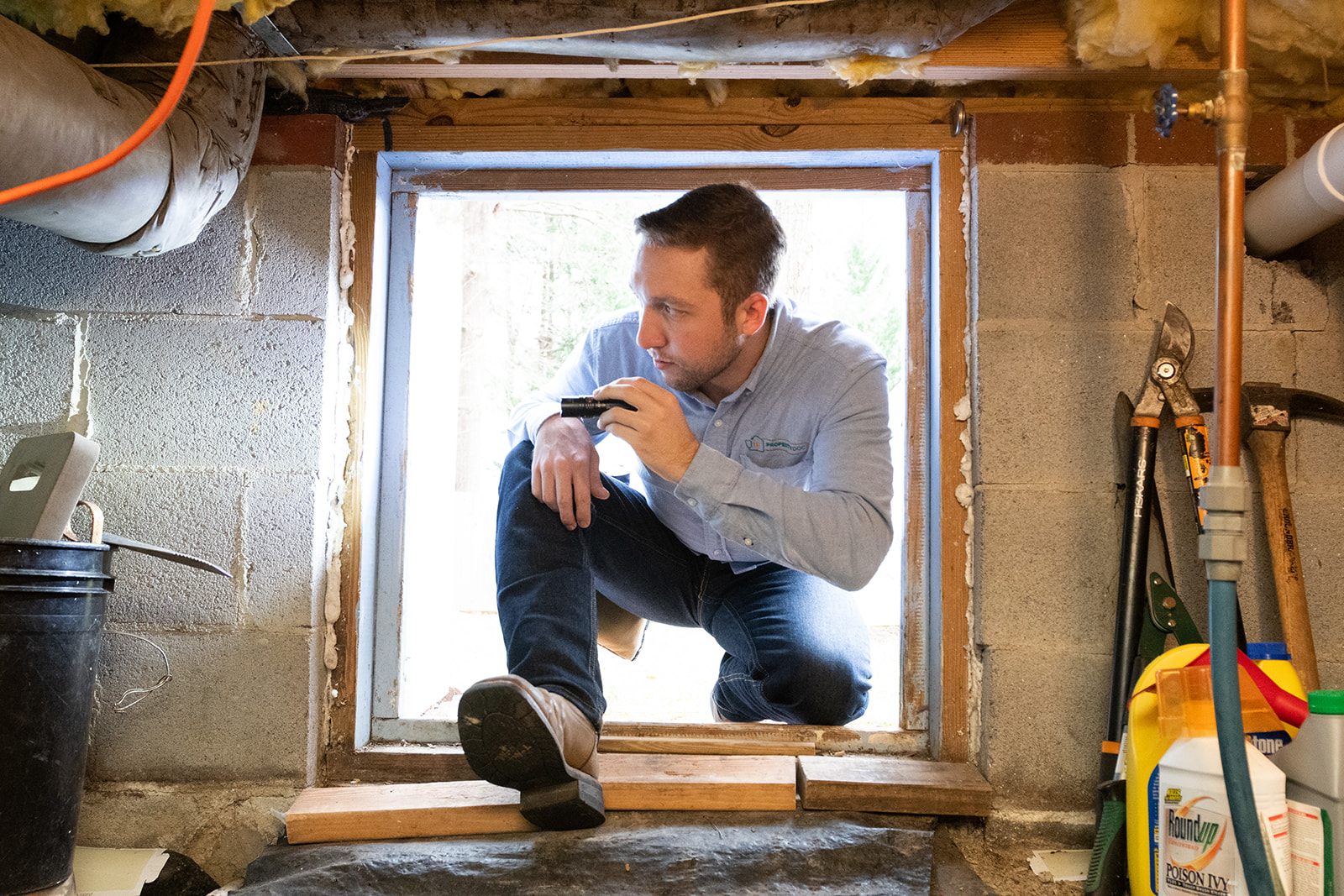Dylan Morgan inspecting a home's crawlspace with a flashlight